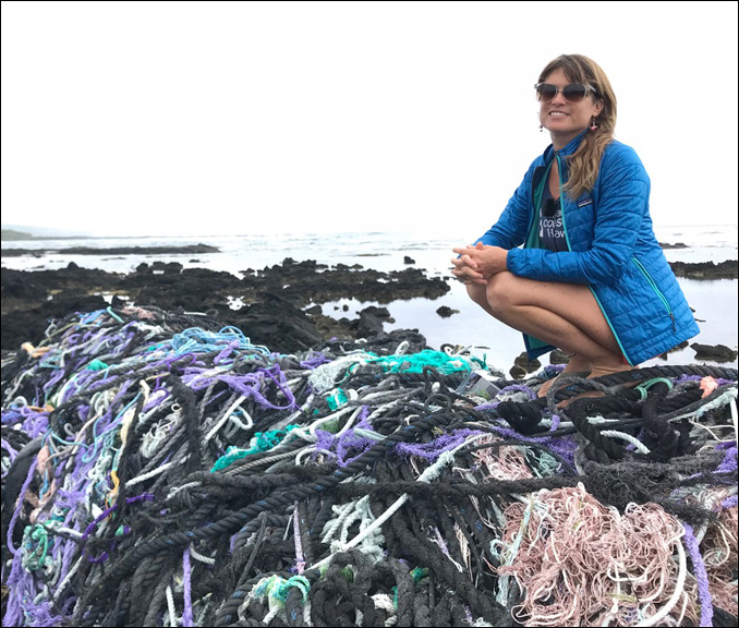 Sarah-Jeanne Royer perches on mound of nets washed ashore in Hawai'i.